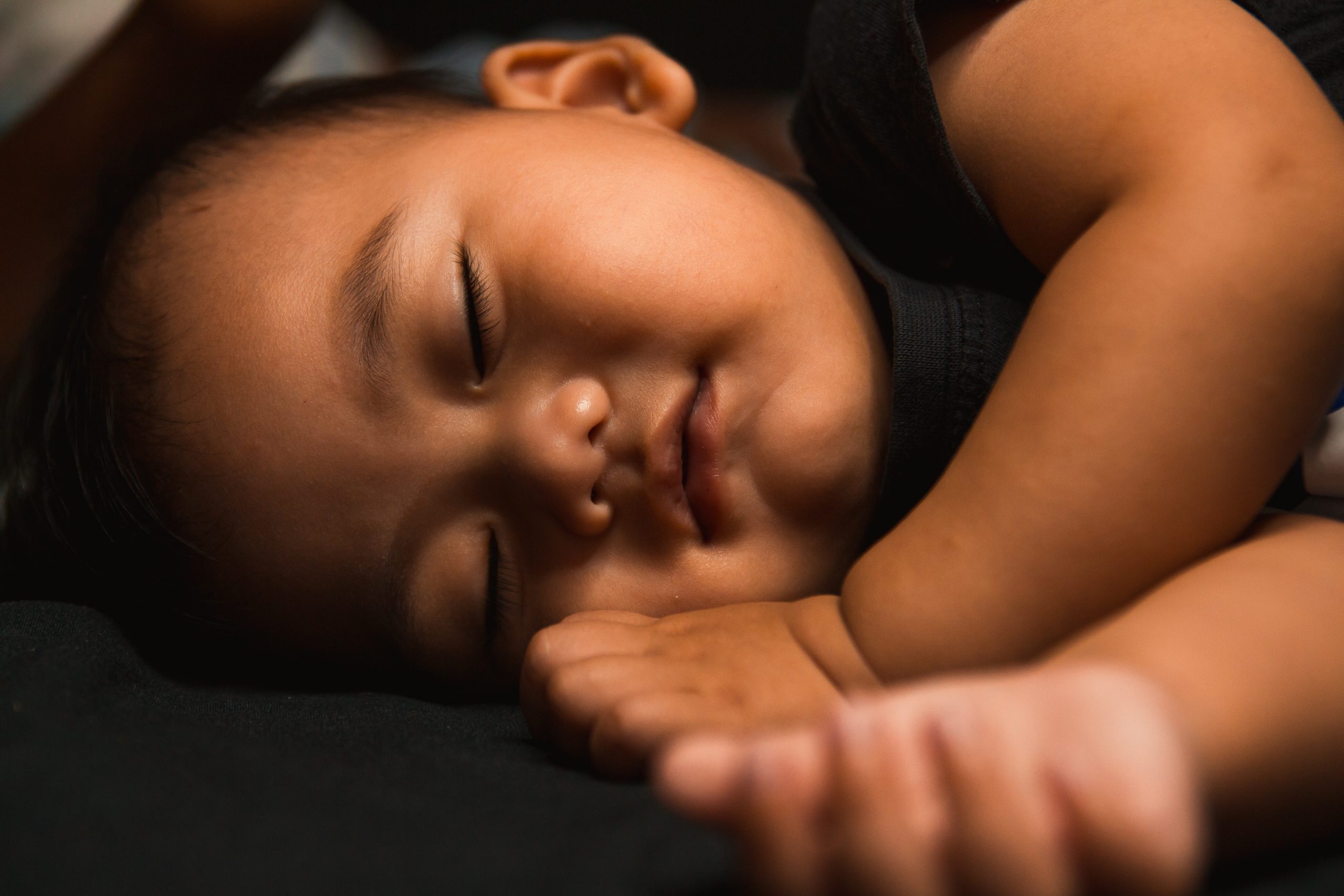 baby lying on a bed in a cooler room so that he can sleep in the heat
