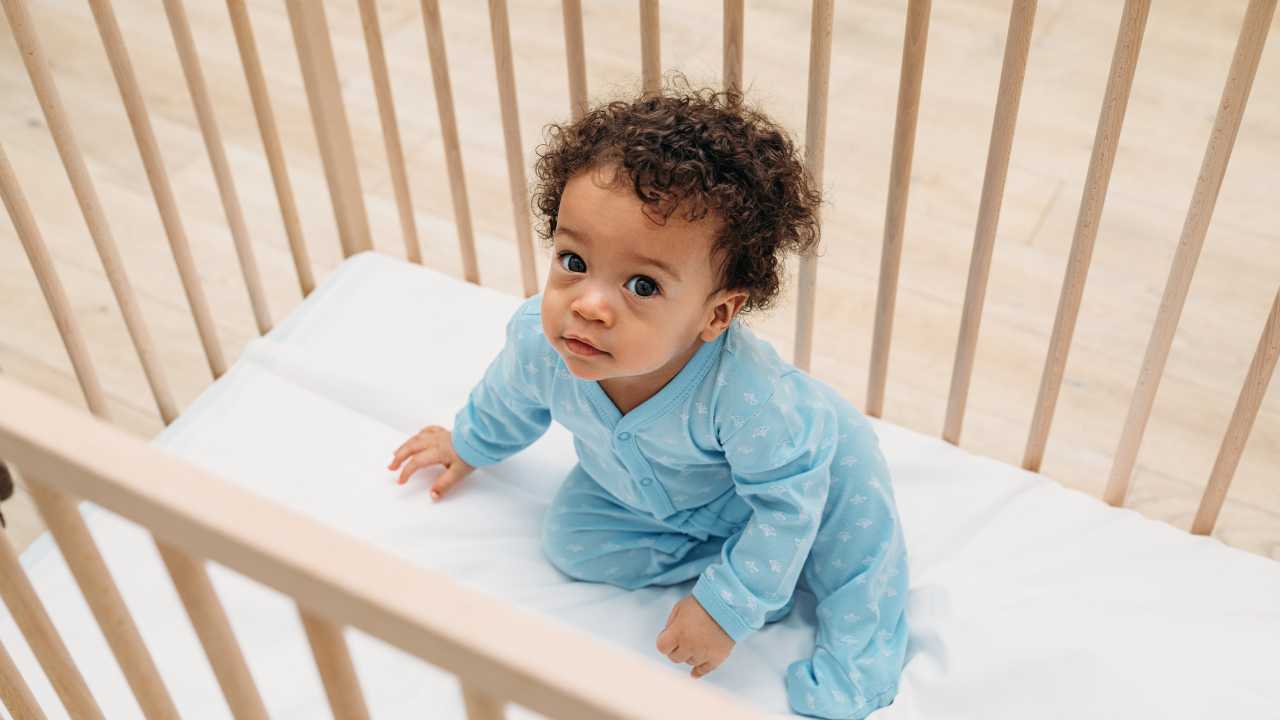 baby sitting in cot ready to work with holistic sleep coach