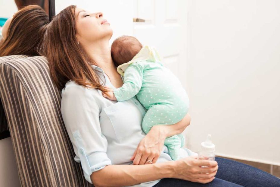 a mum sitting on a chair with her baby after a night feed wondering when her baby will start sleeping through the night