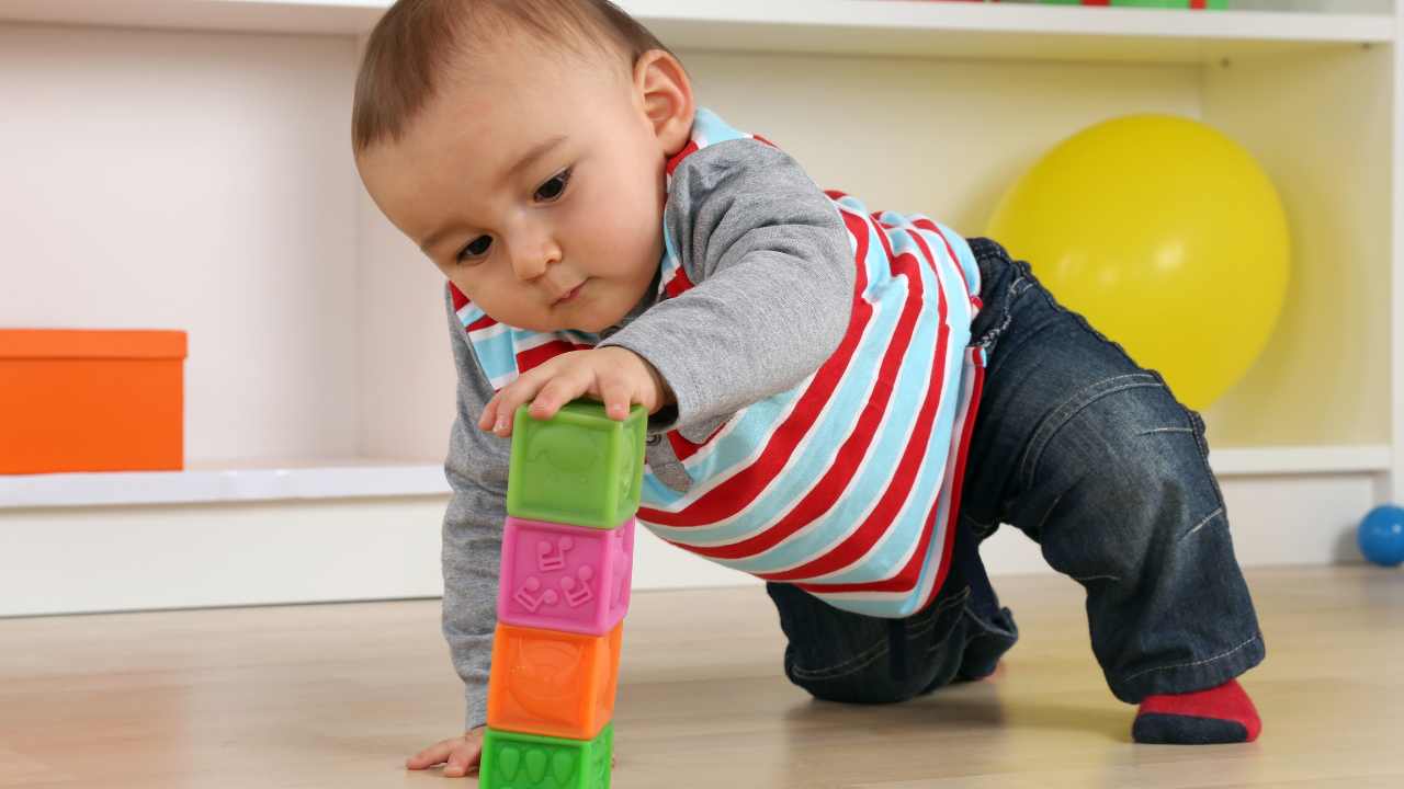 9 month old boy playing with building blocks at nursery