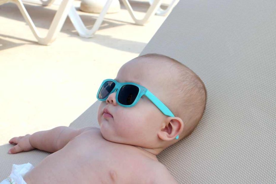 baby lying on the beach wearing sunglasses in the summer