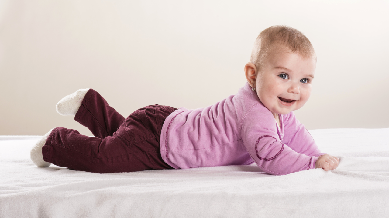 a baby lying on a floorbed