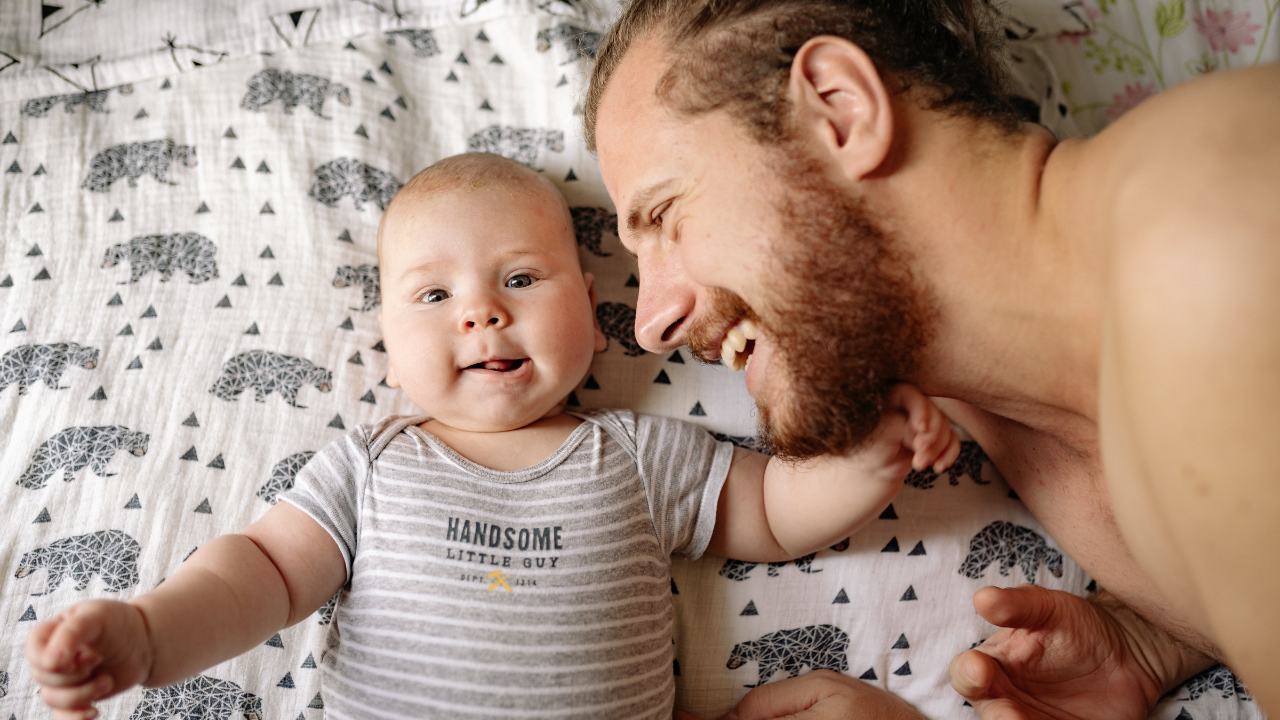 Dad lying on bed with baby as he's now able to settle